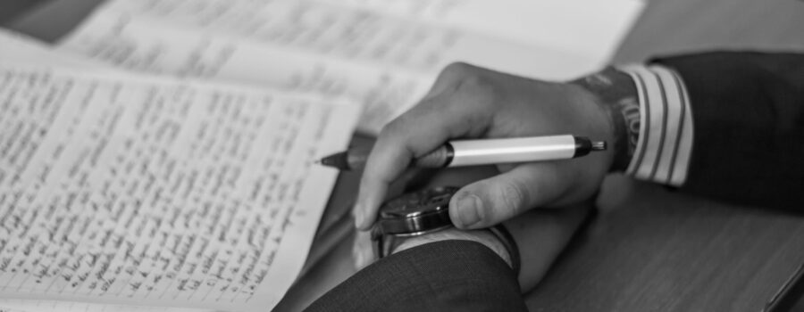 grayscale photography of person holding pen